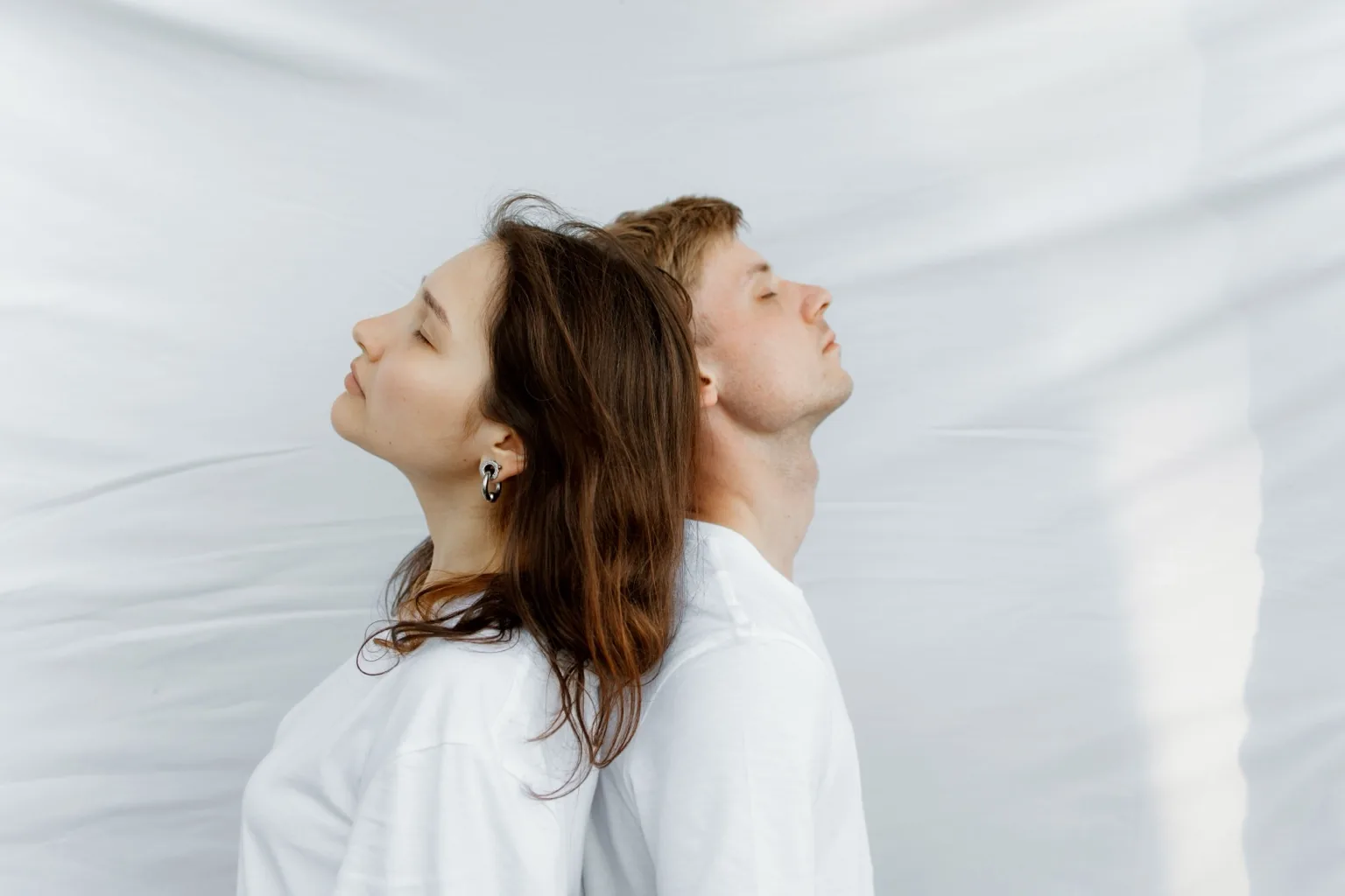 Two people resting back to back in a calm setting
