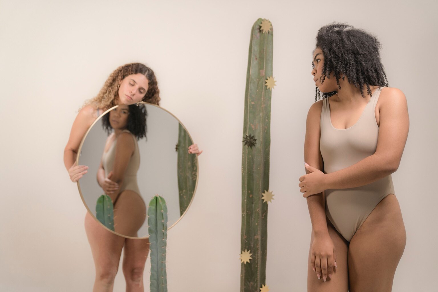 Two women looking toward a mirror, representing body image and self-perception