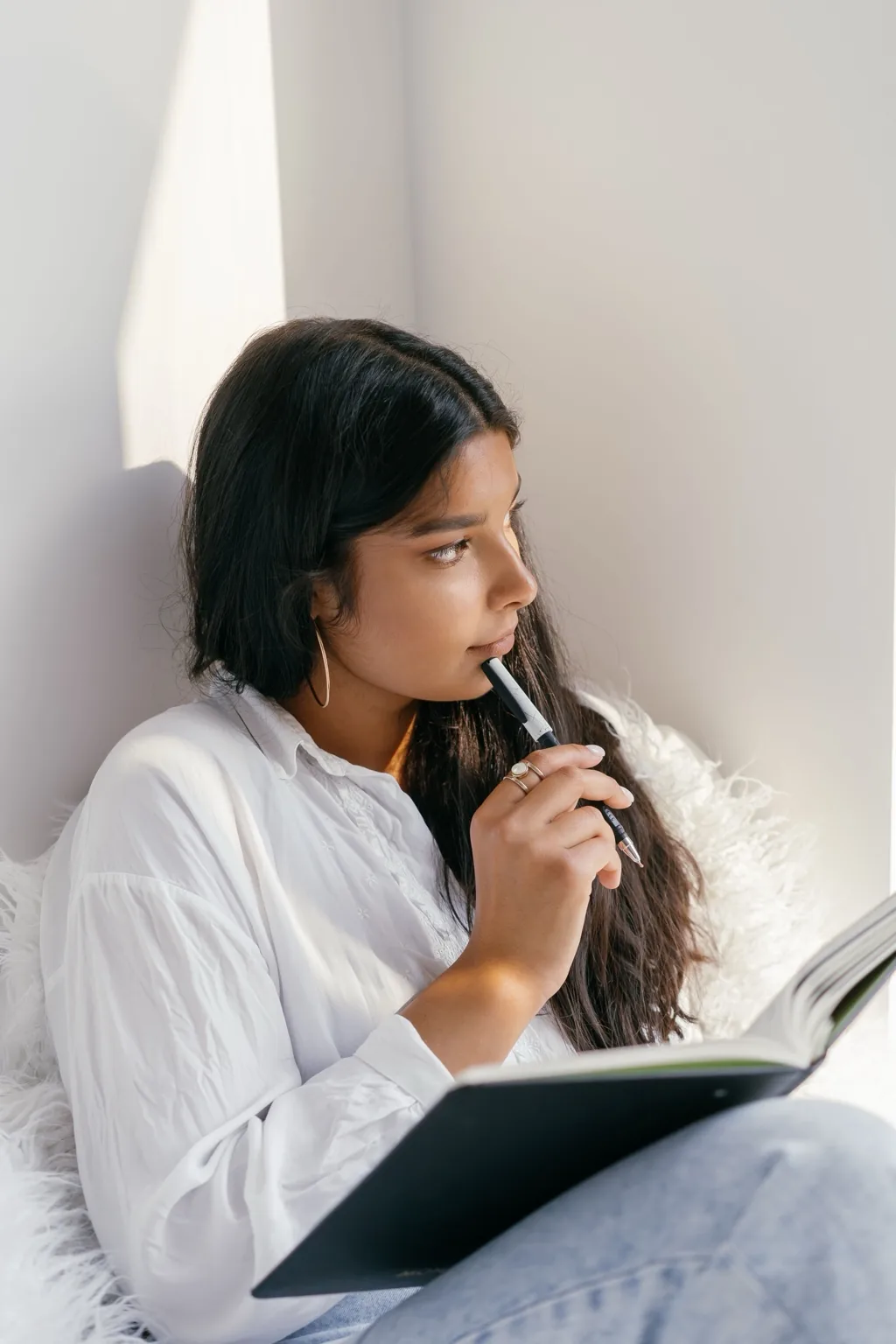 A woman thoughtfully writing in a notebook