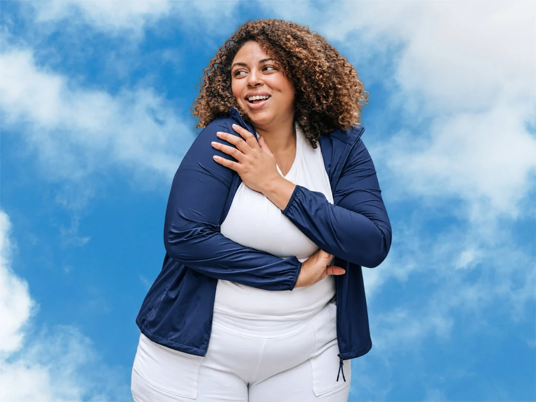 Smiling woman in a navy jacket against a blue sky