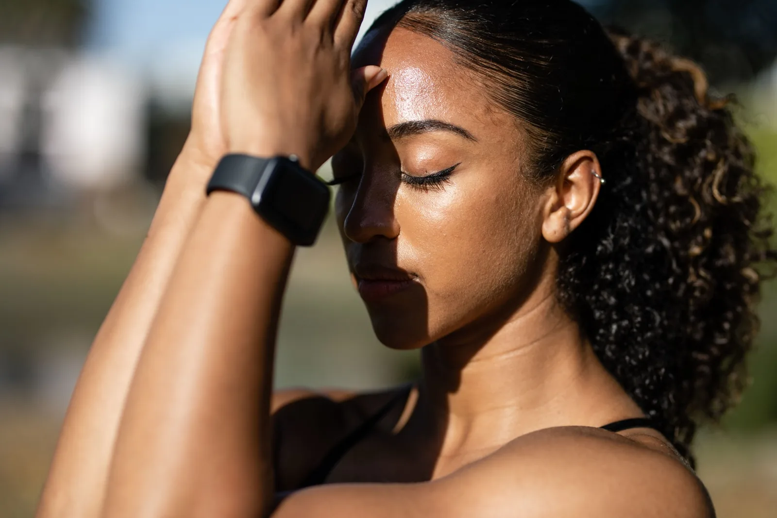 Woman outdoors pausing during a walk and checking her fitness watch